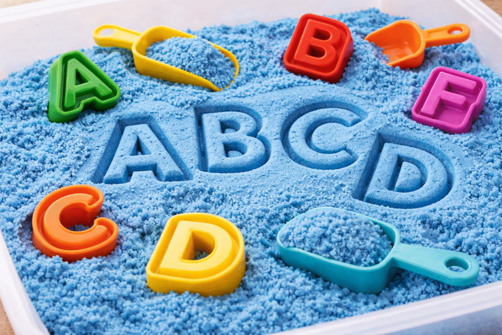 blue kinetic sand for sensory play with letters  imprinted on the sand

